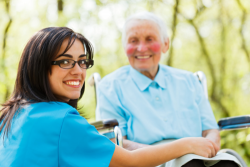 caregiver smiling with an elderly woman in a wheelchair